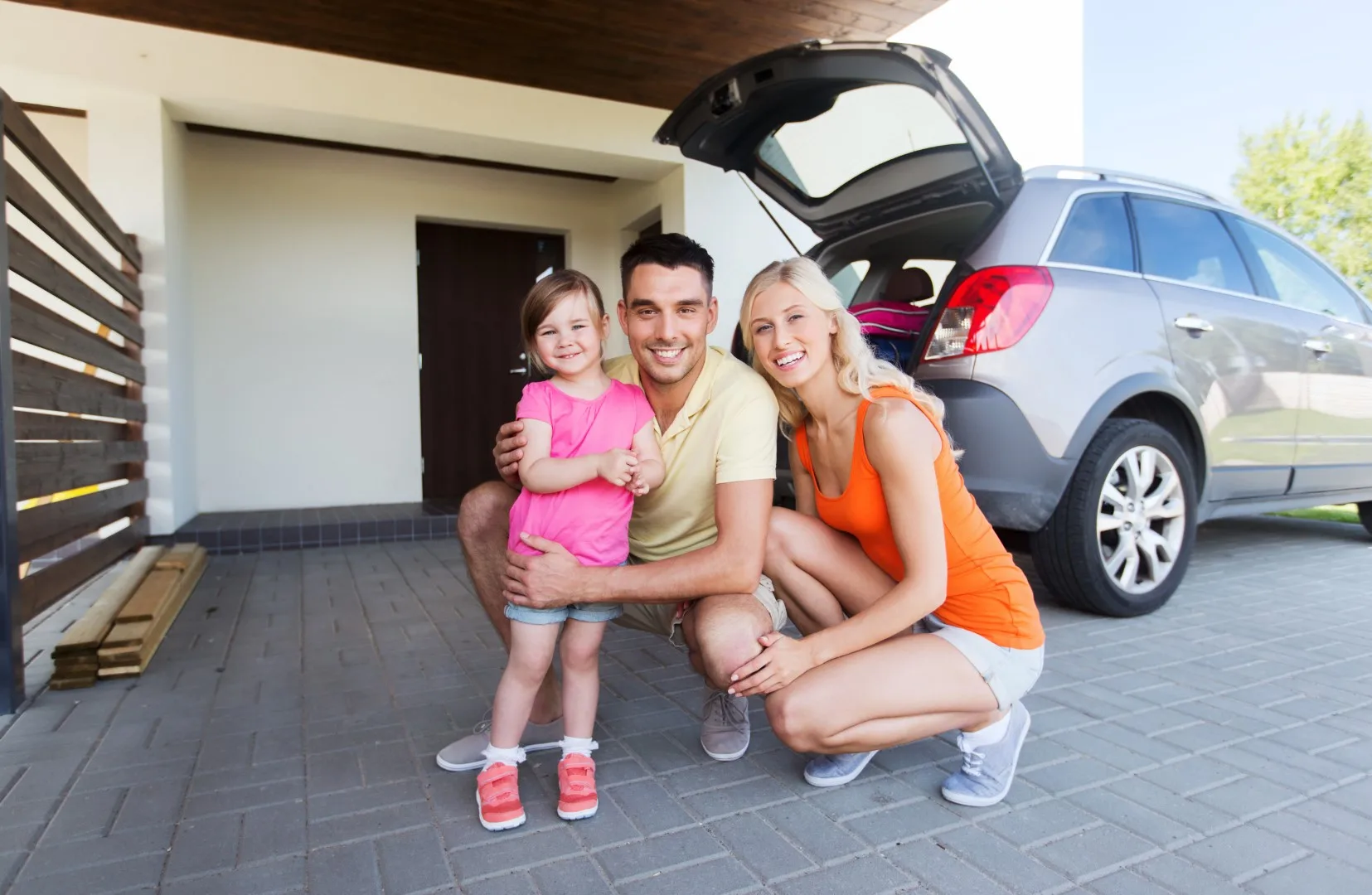 happy family with hatchback car at home parking